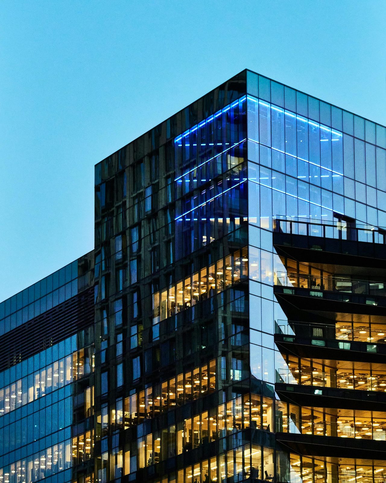 Commercial high-rise glass building lit at dusk